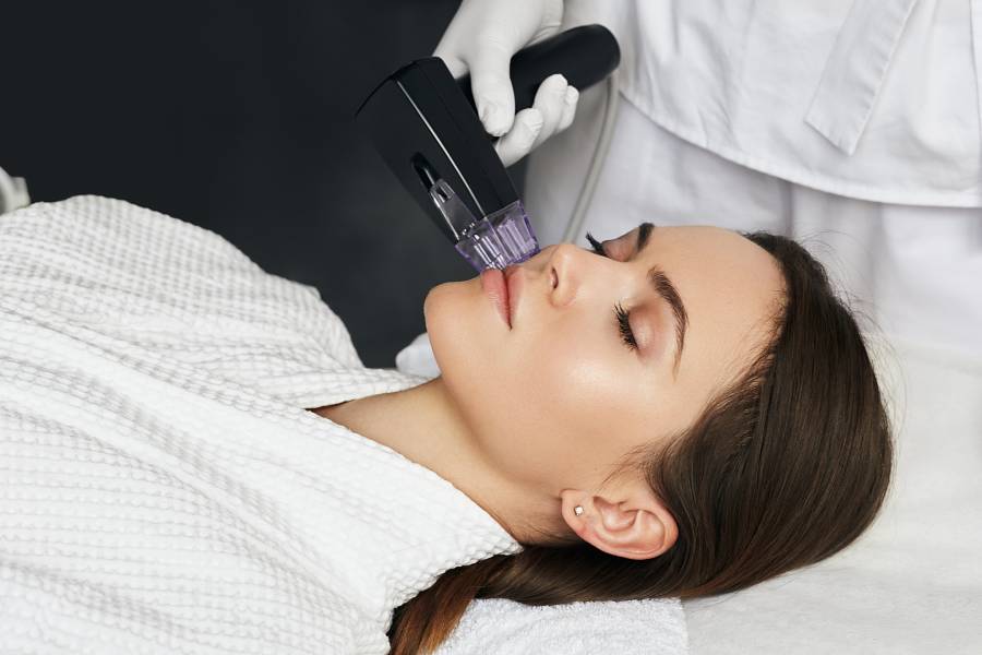 Brunette woman receiving radiofrequency lifting procedure for her face skin rejuvenation at aesthetic cosmetology clinic